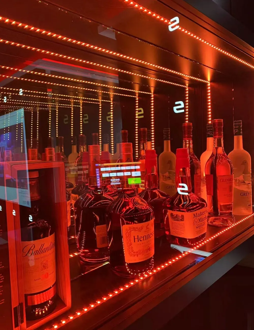 Illuminated liquor cabinet with various spirits at Sister Karaoke, a Karaoke bar in Buena Park